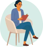 A woman looking serious, wearing glasses and a blue jacket, white top and blue trousers. She is sat in a beige chair with her legs crossed holding a clipboard which she is writing on.